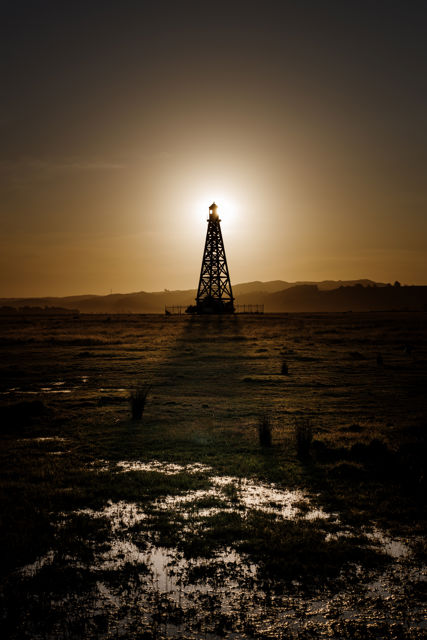 Lit - The taller of two abandoned shipping beacons near Hawke's Bay airport lit from the setting sun behind